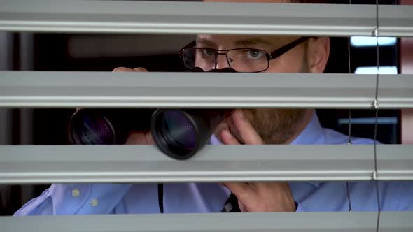 A businessman in Glasses and with Binoculars in Hands Wants to spy on the Neighbor.