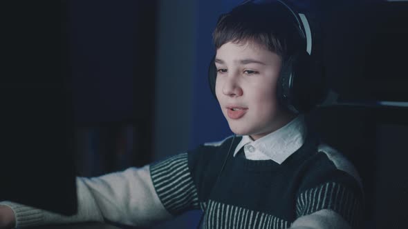 Smiling Boy in Headphones Making Video Call While Sitting at Computer Laptop Late at Night