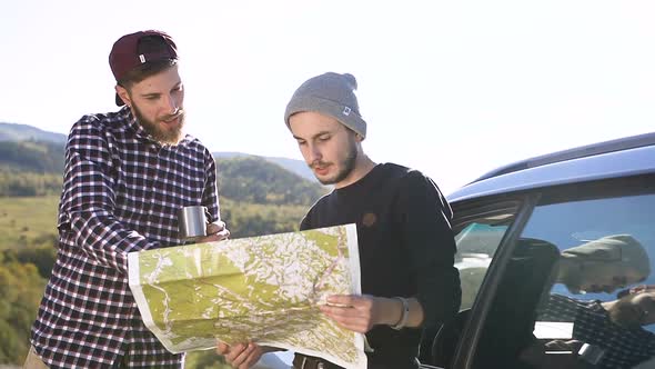 Two Hipster Men Researching Area on the Map for Hike in the Mountain