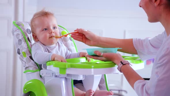 Cute Blond Boy Play with Spoon Eating in Highchair