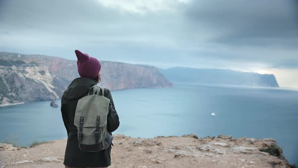 Hipster Travel Woman Admiring Seascape Nature Landscape with Cloudy Dramatic Sky From Top Mountain