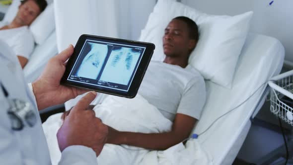 Close-up of Caucasian male doctor looking at x-ray report on digital tablet in the ward