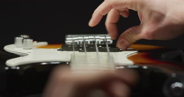 Close up of fingers strumming an electric guitar