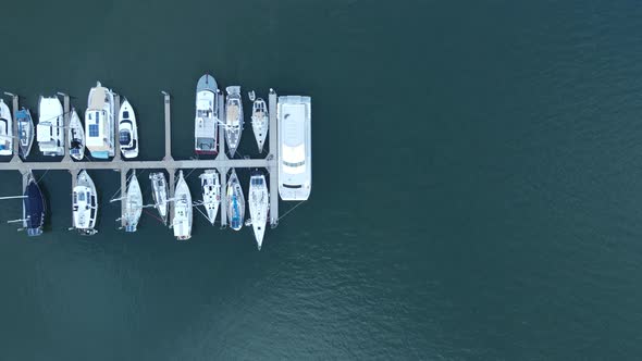 Aing drone view looking down at multiple boats docked on a wharf in a protected harbor located in th