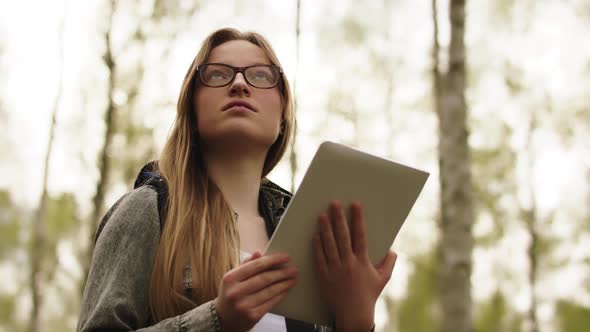 Young Woman, Traveler Using Tablet To Navigate Through the Forest