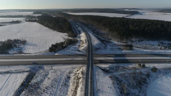 The camera flies over the railway and approaches the highway. Around the forest and snow fields 03
