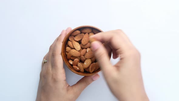 Top View of Women Hand Rating Almond Nuts From a Bowl