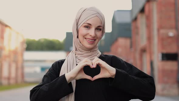 Beautiful Young Muslim Woman Smiling Confident Enthusiastic and Cheerful with Hands Sign of Love