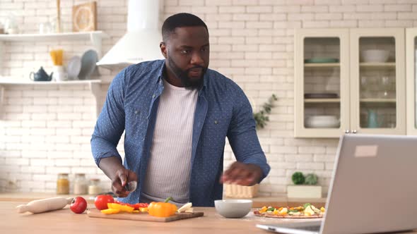 AfricanAmerican Man Watching Cooking Video Tutorial on the Laptop