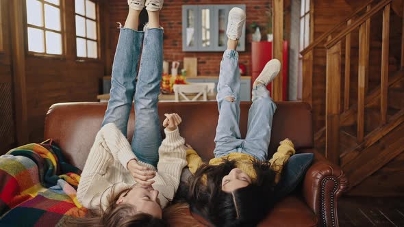 Mother and Little Daughter Falling Down on Couch with Their Feet Up Laughing Tickling Each Other