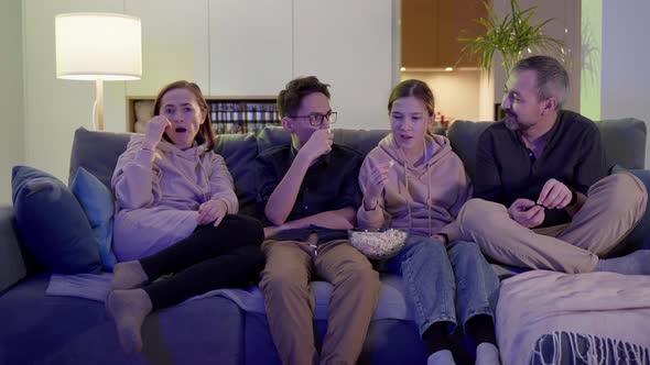 Portrait of a Happy Family Watching TV on the Sofa in the Evening in the Living Room