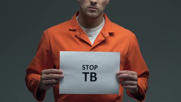 Stop TB Phrase on Cardboard in Hands of Caucasian Prisoner, Healthcare Need