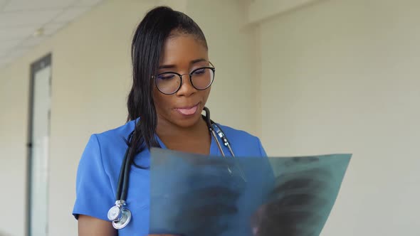 A Young AfricanAmerican Female Doctor in a Blue Suit Stands in the Hallway of the Clinic and