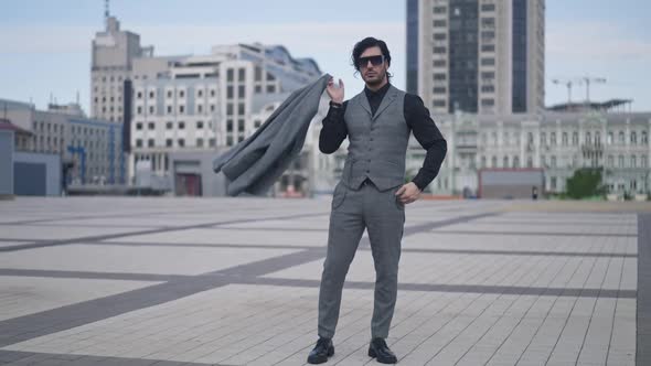 Wide Shot Portrait of Confident Wealthy Young Caucasian Man Standing on City Square Hanging Blazer
