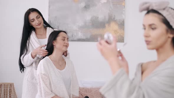 A Close View of a Beautiful Woman Doing Her Make-up and Two Girls Behind