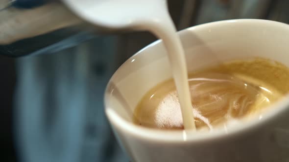 Barista steaming milk. barista whips milk in a pitcher with hot steam from coffee machine.