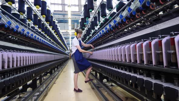 Female Worker is Adjusting Thread Spools in the Factory Machines