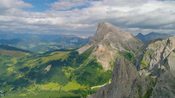 Aerial view overlooking Peitlerkofel South Tyrol rocky mountain range with illuminated meadow valley