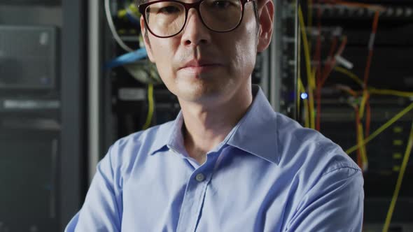 Portrait of smiling asian male it technician by computer server