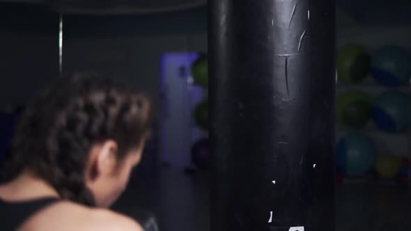 Young Woman in Boxing Gloves Training with a Punching Bag in a Boxing Club