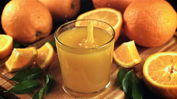 A Drop of Orange Juice Falls Into a Full Glass of Spray