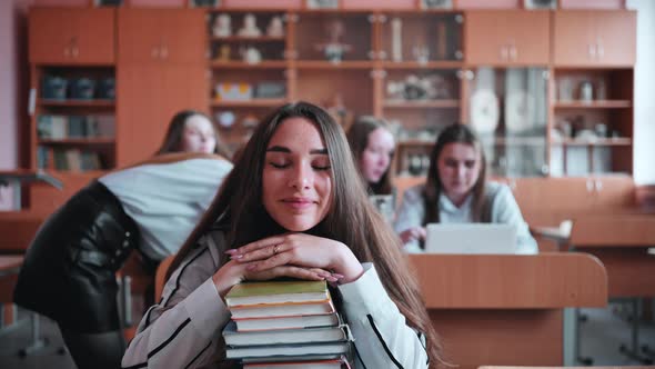 A Student Poses with Textbooks at Her Desk in Her Class