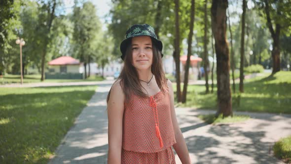 A Teenage Girl in a Panama Hat is Walking Through the Park in the Summer