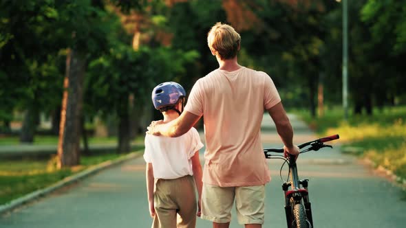 A back view of a father with his son is going to ride a bicycle