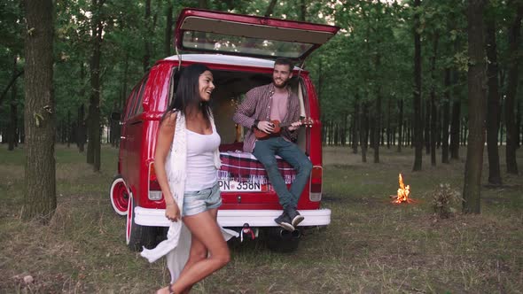 Happy Young Cheerful Mixed Race Couple Having Some Fun in Retro Hippie Minibus in Forest