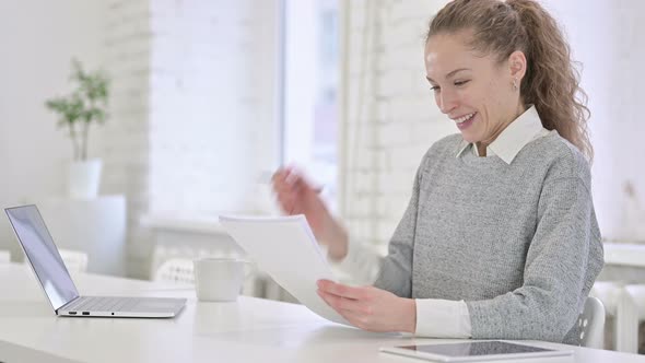 Young Latin Woman Celebrating Success on Documents 