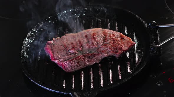 beef steak steaming cooking in a pan on an induction plate