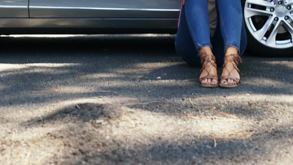 Depressed woman sitting near car