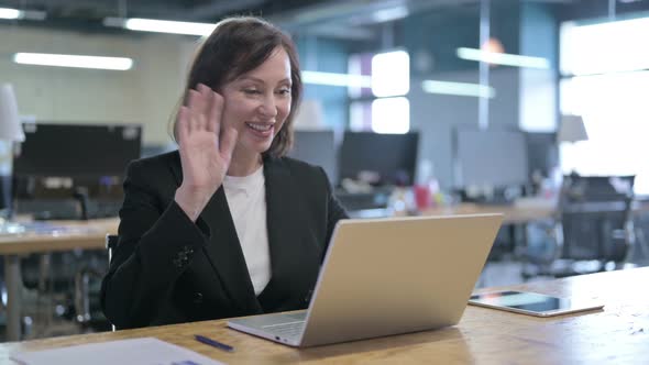 Cheerful Middle Aged Businesswoman Doing Video Chat on Laptop in Office