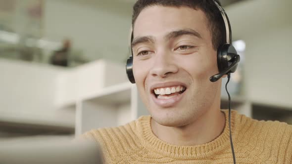 Smiling Handsome Latinos Man Communicates Via Video Link with a Headset on His Head Consulting