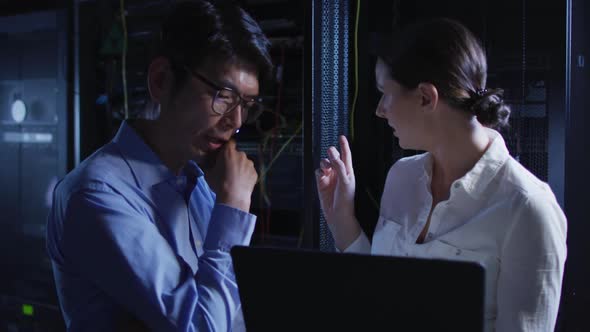 Diverse female and male it technicians using laptop checking computer server