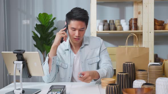 Asian young attractive busy business man working alone in warehouse.