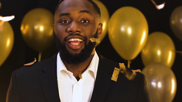 Afro-American Man Standing Under Falling Confetti and Winking to Camera, Party