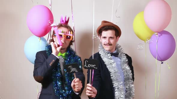 Two men holding boards in love in photo booth