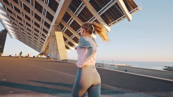 Millennial Female Jogging By Embankment Area of Modern Coastal City