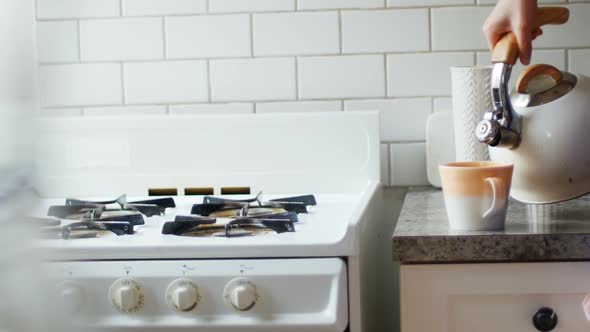 Woman pouring water into mug from kettle