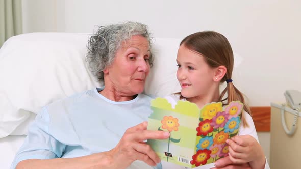 Smiling mother and girl sitting on the bed of a patient