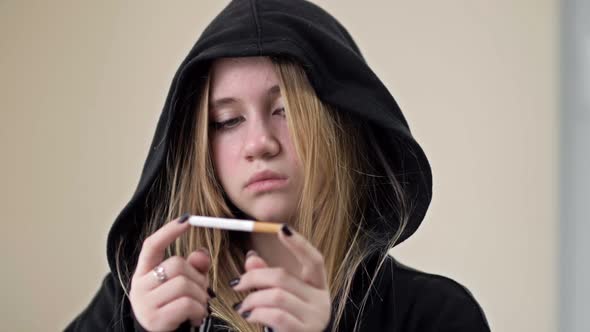 Teenage Girl Breaks a Cigarette