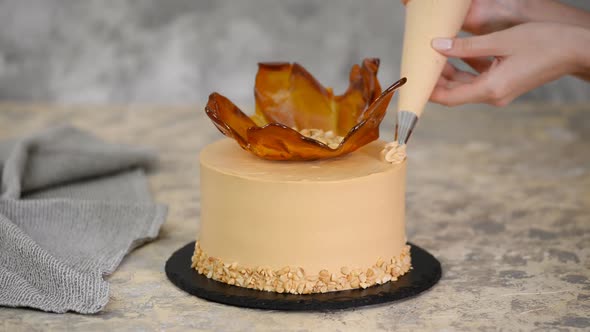 Close up woman's hand decorating cake with caramel cream.