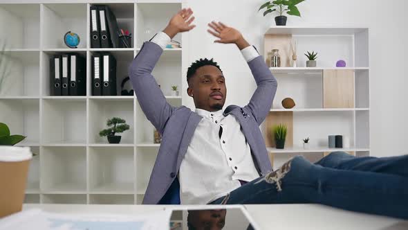 Black-Skinned Office Manager Puting His Feet on Work Table and Resting After Finishing Work