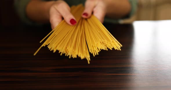 Woman hand holding italian uncooked spaghetti whole grain pasta in the kitchen at home.