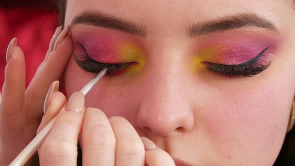 A Special Thin Brush Applies Black Eyeliner Under the Eyes of the Model