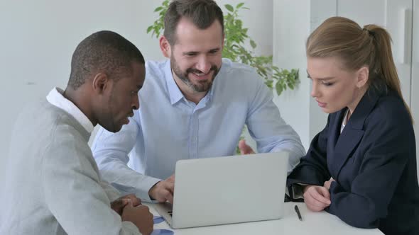 Mixed Race Business People Celebrating Success While Using Laptop in Office