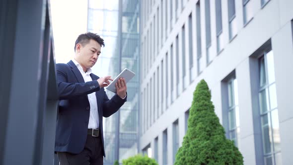 young asian businessman standing near the railing of terrace a modern office building 