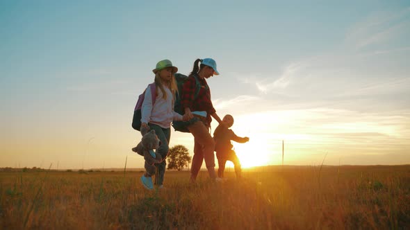 Mother and Two Children Walking in the Meadow at the Sunset Time. Silhouette Happy Beautiful Family