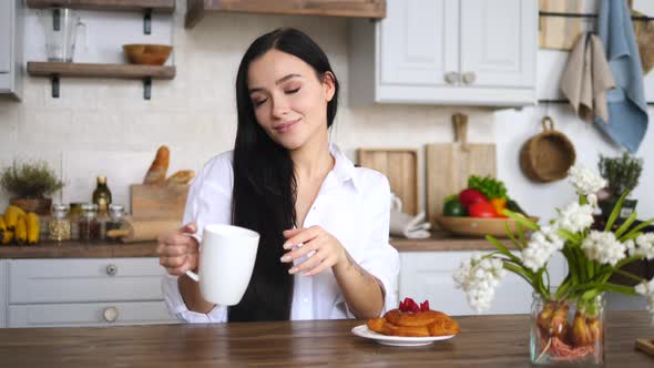 Smiling Happy Woman Holding Cup Of Coffee In Kitchen